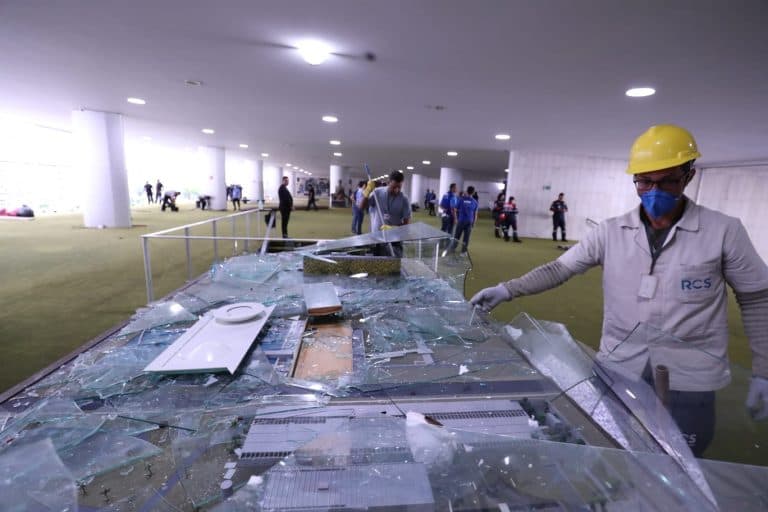 Trabalhadores recolhem destroços da maquete tátil do Congresso após os ataques de 8 de janeiro.