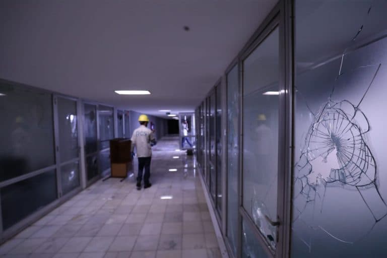 Vidros quebrados num corredor da Câmara e um trabalhador ao fundo.