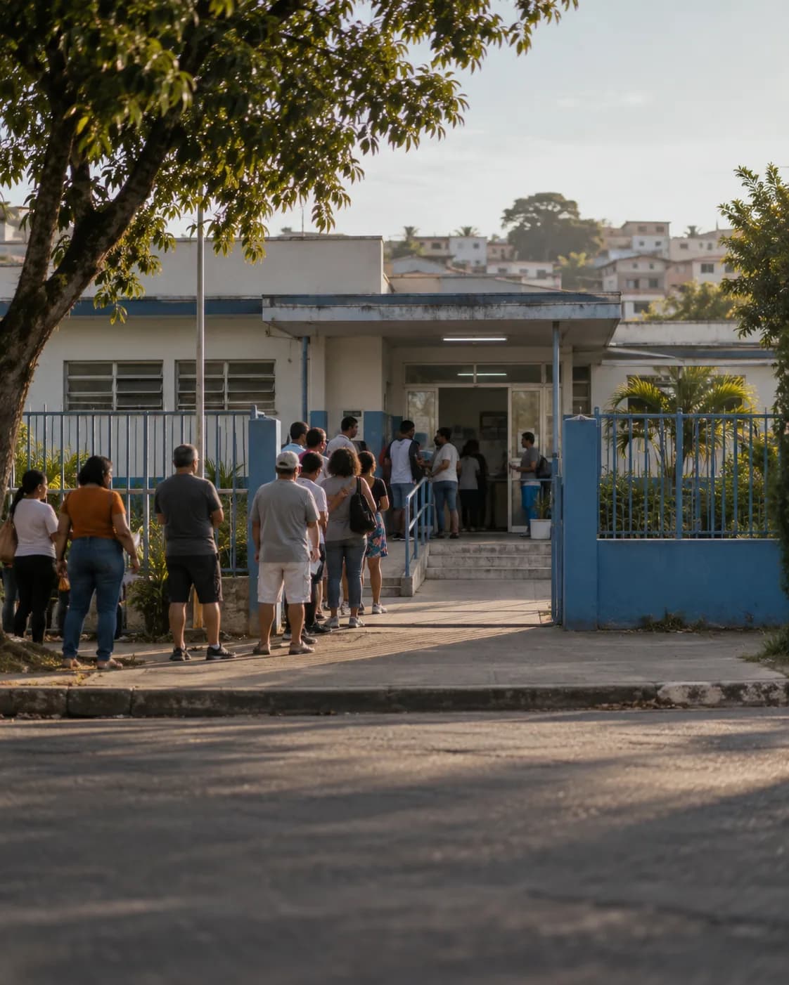 posto de saúde de bairro com a porta de entrada e uma fila de pessoas aguardando, fotografada de longe.