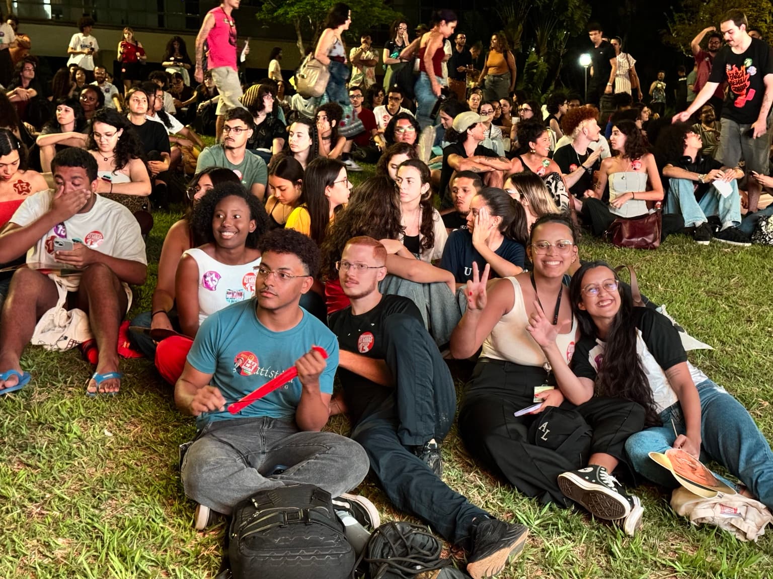 Grupo de estudantes acompanha a assembleia sentado no gramado da UFMG