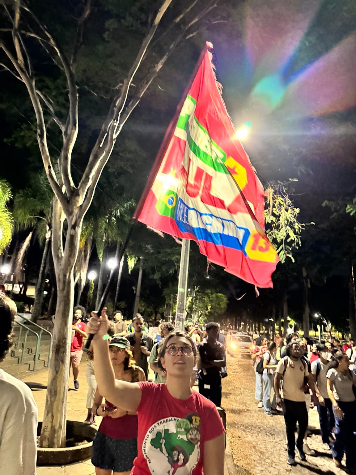 Participante ergue uma bandeira durante a caminhada de estudantes no campus da UFMG