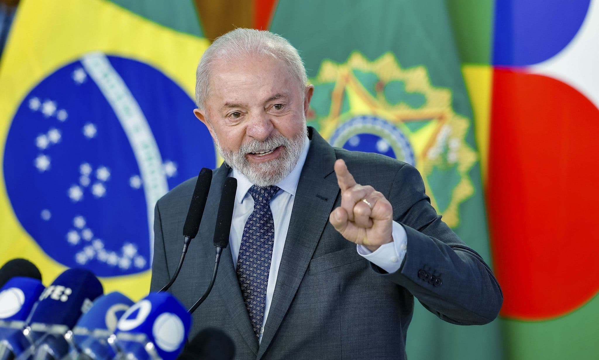 Fotografia real de Lula discursando diante de bandeiras brasileiras. Imagem de arquivo, não da cerimônia do Prospera MEI.