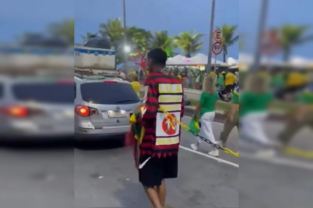 Registro de Raphaël Bernard mostra homem negro ligado por corrente a outro manifestante em ato pró-Flávio na Barra da Tijuca, em 24 de outubro de 2026.