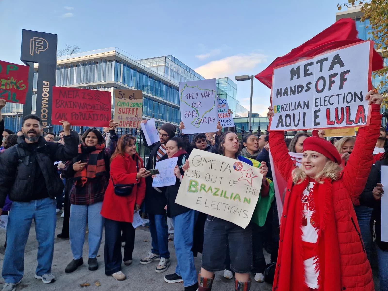 Manifestantes brasileiros seguram cartazes diante da sede da Meta em Dublin em 16 de outubro de 2026. A fotografia registra o ato na Irlanda, não a mobilização prevista em São Paulo.