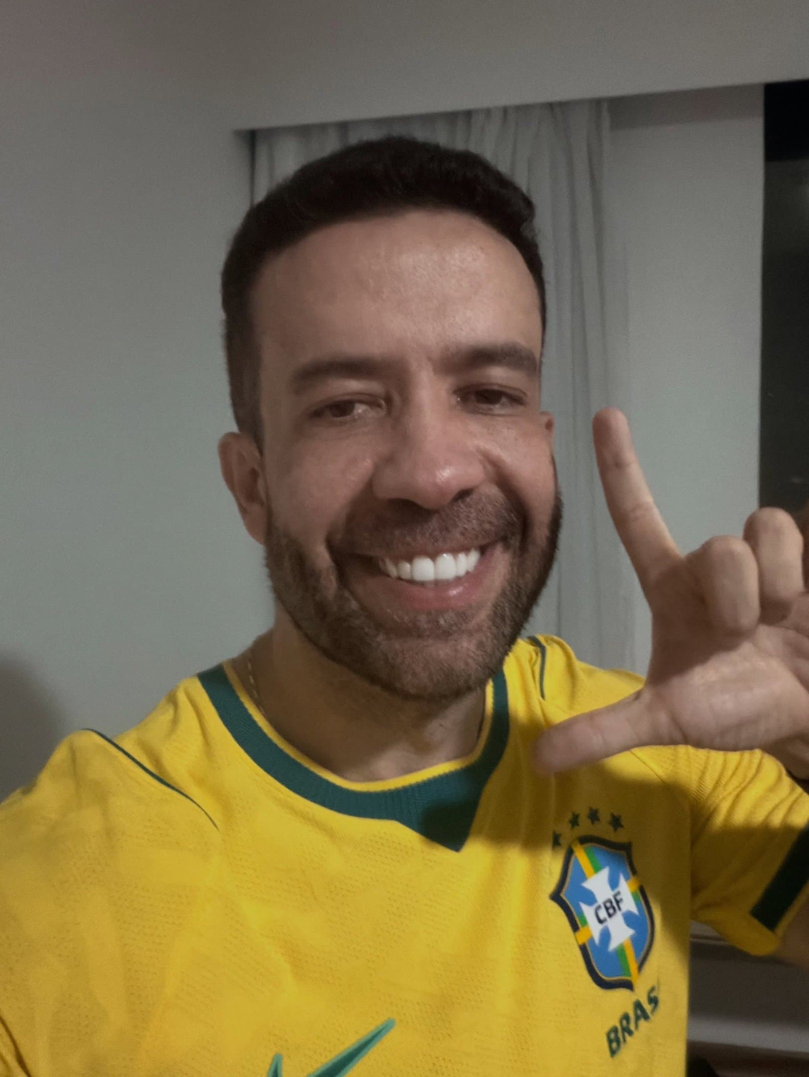 André Janones sorri com a camisa da Seleção Brasileira e faz o L em fotografia divulgada na mobilização de 17 de outubro de 2026.