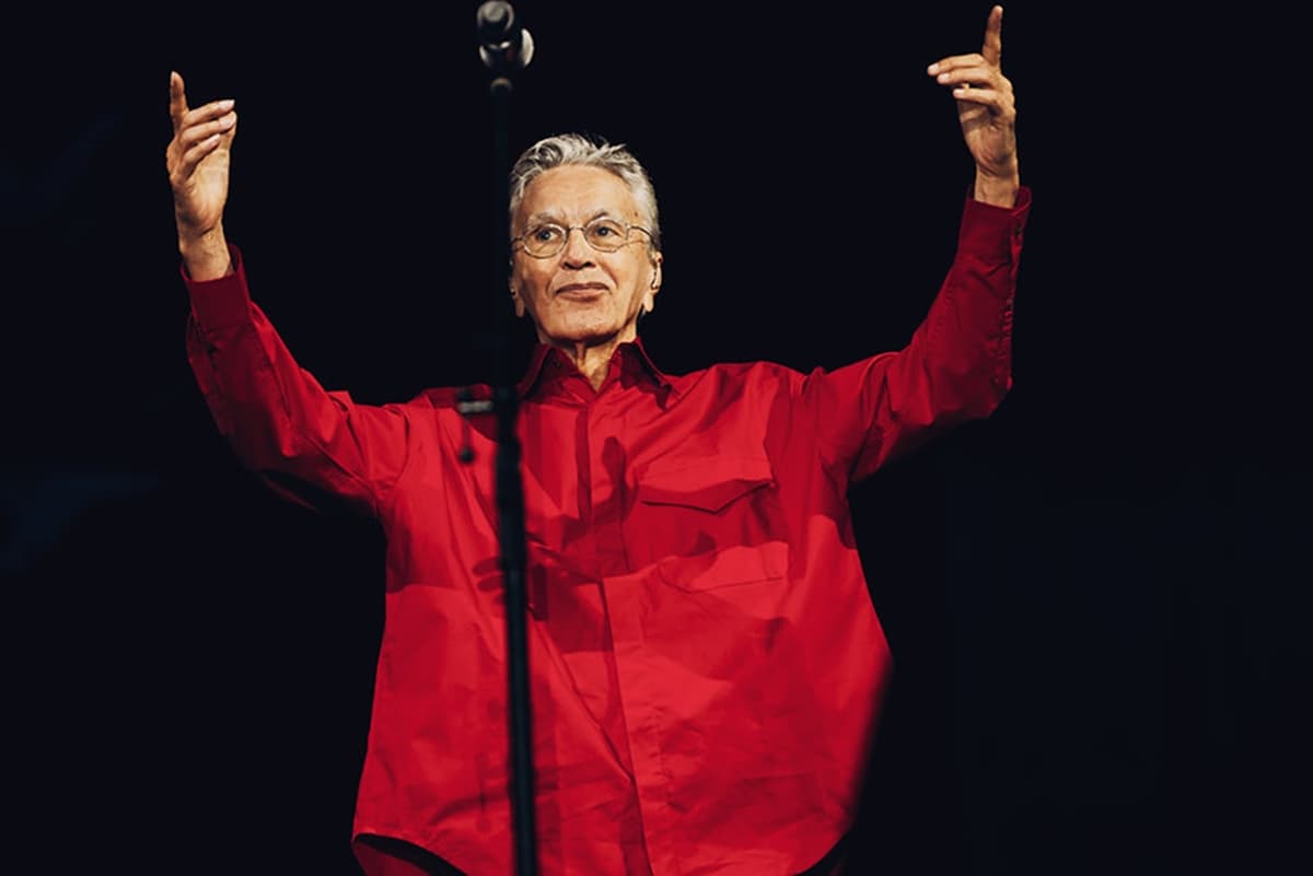 Caetano Veloso, de camisa vermelha e braços erguidos, em apresentação anterior no Taguaparque. A fotografia não registra o ato de 18 de outubro.