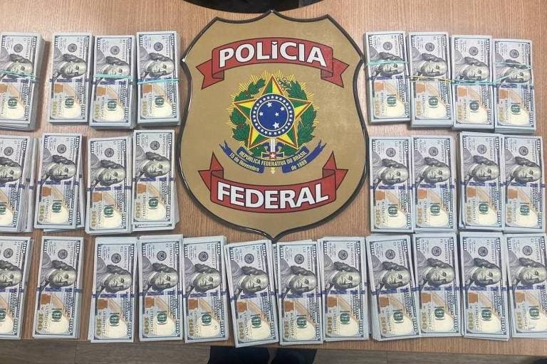 Dólares em espécie apreendidos pela PF com Paulo Maurício Fortunato em 20 de outubro de 2023, organizados sobre uma mesa.