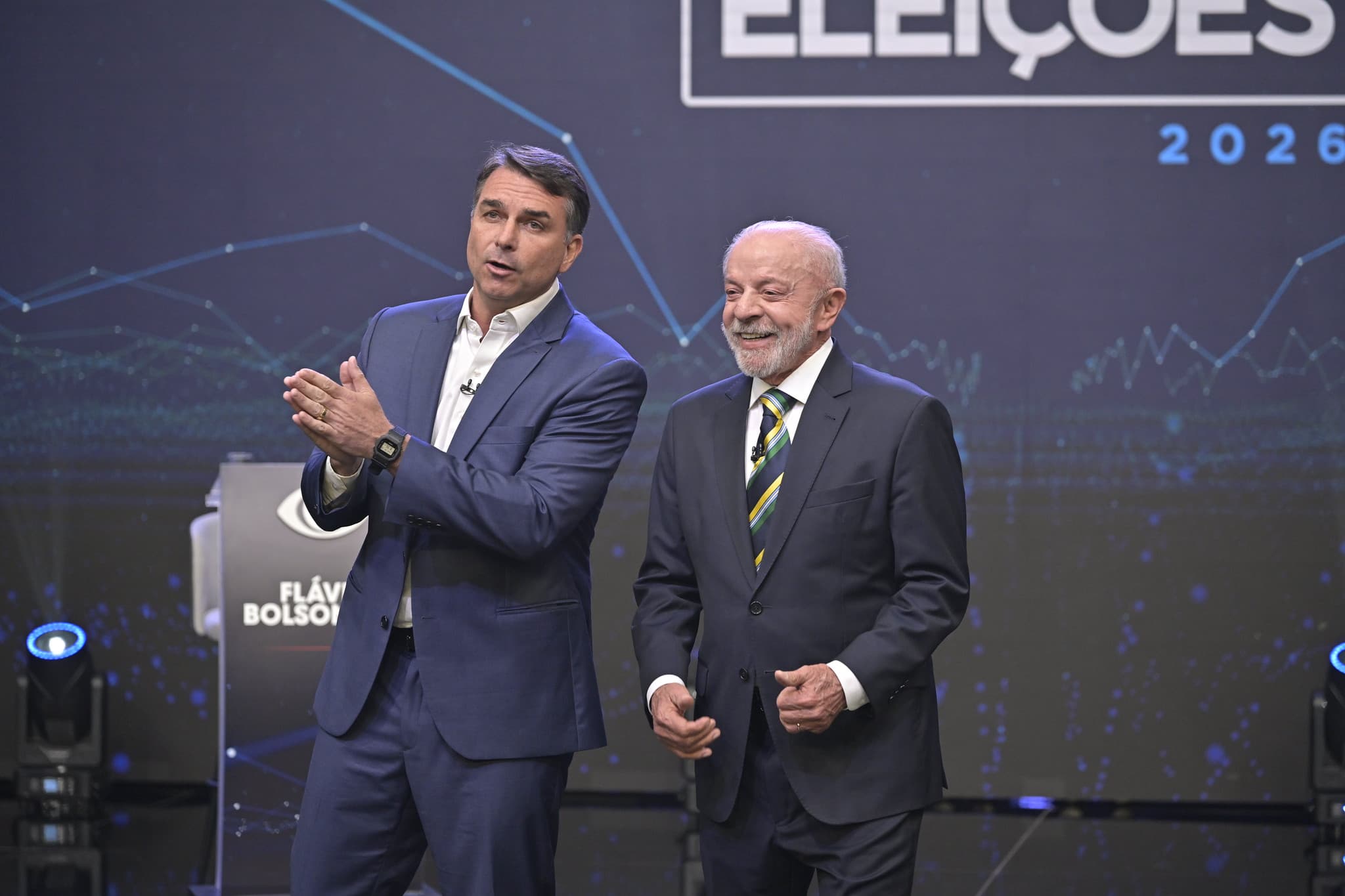 Flávio Bolsonaro e Lula lado a lado no palco do debate da Band, em São Paulo, em 18 de outubro de 2026.