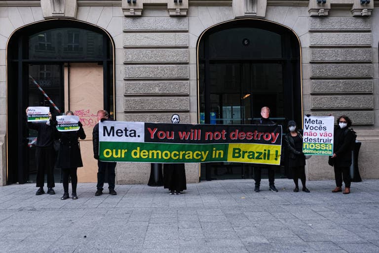 Brasileiros protestam diante da Meta em Paris em 16 de outubro de 2026, com faixas em defesa da democracia brasileira.