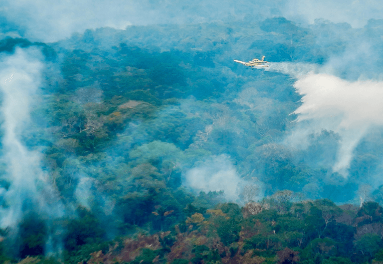 Aeronave sobrevoa floresta coberta por fumaça em registro divulgado pelo MMA sobre o combate aos incêndios no Amazonas em outubro de 2026.