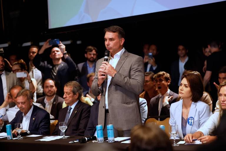Flávio Bolsonaro fala ao microfone durante reunião com parlamentares do PL.